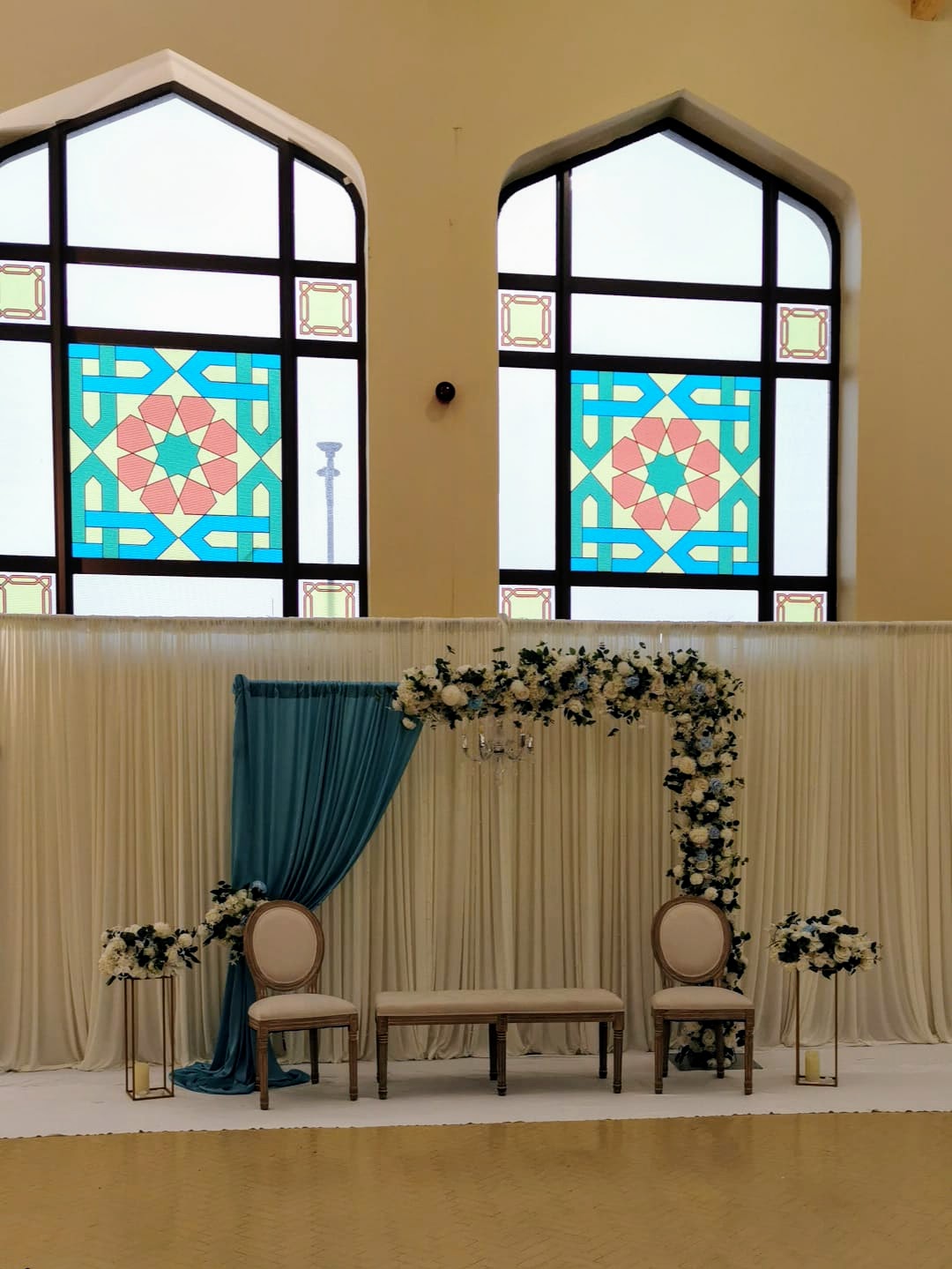 Nikah stage with floral arch and Islamic stained glass windows
