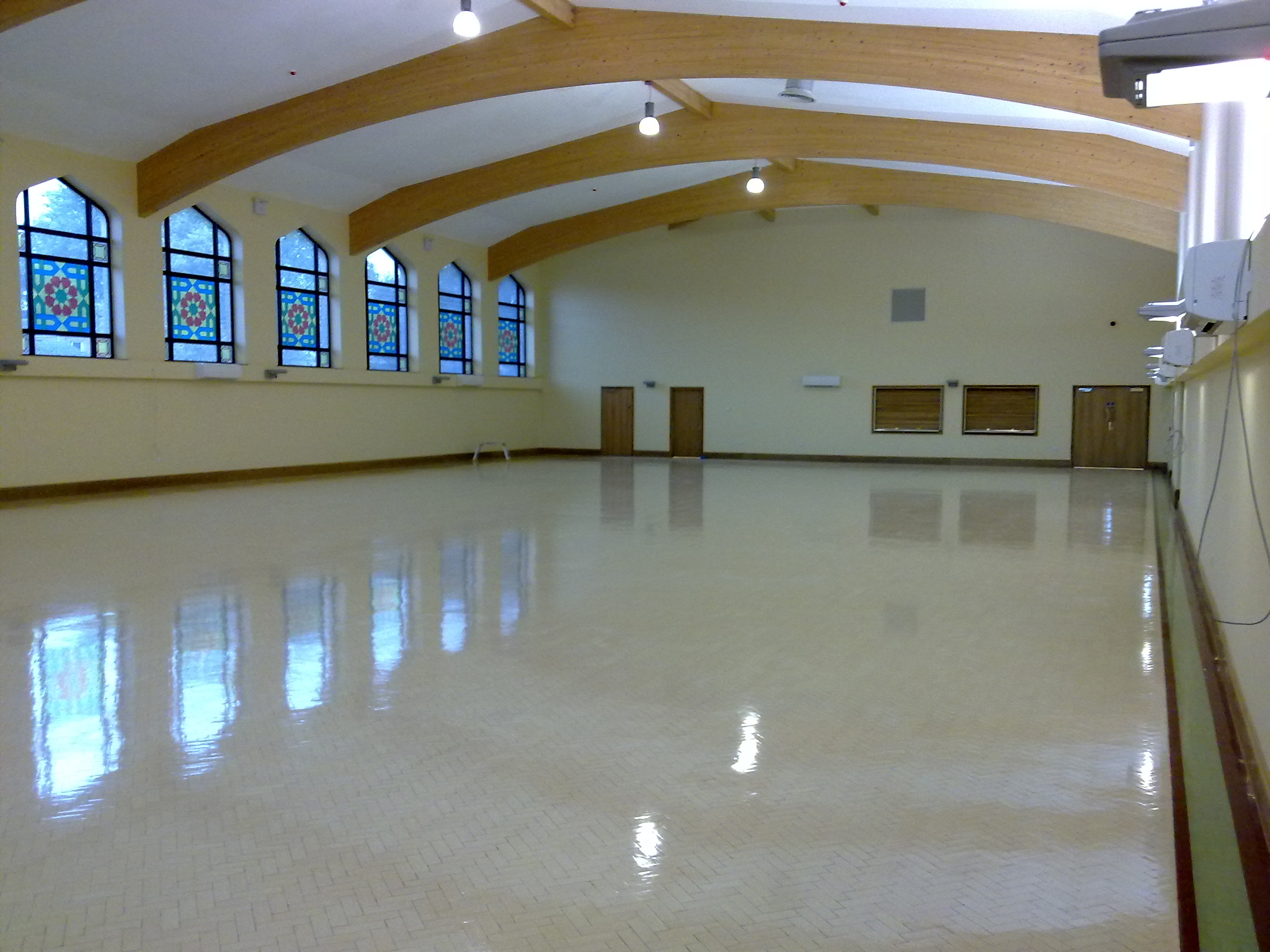 Community centre hall — spacious empty venue with stained glass windows and timber beams