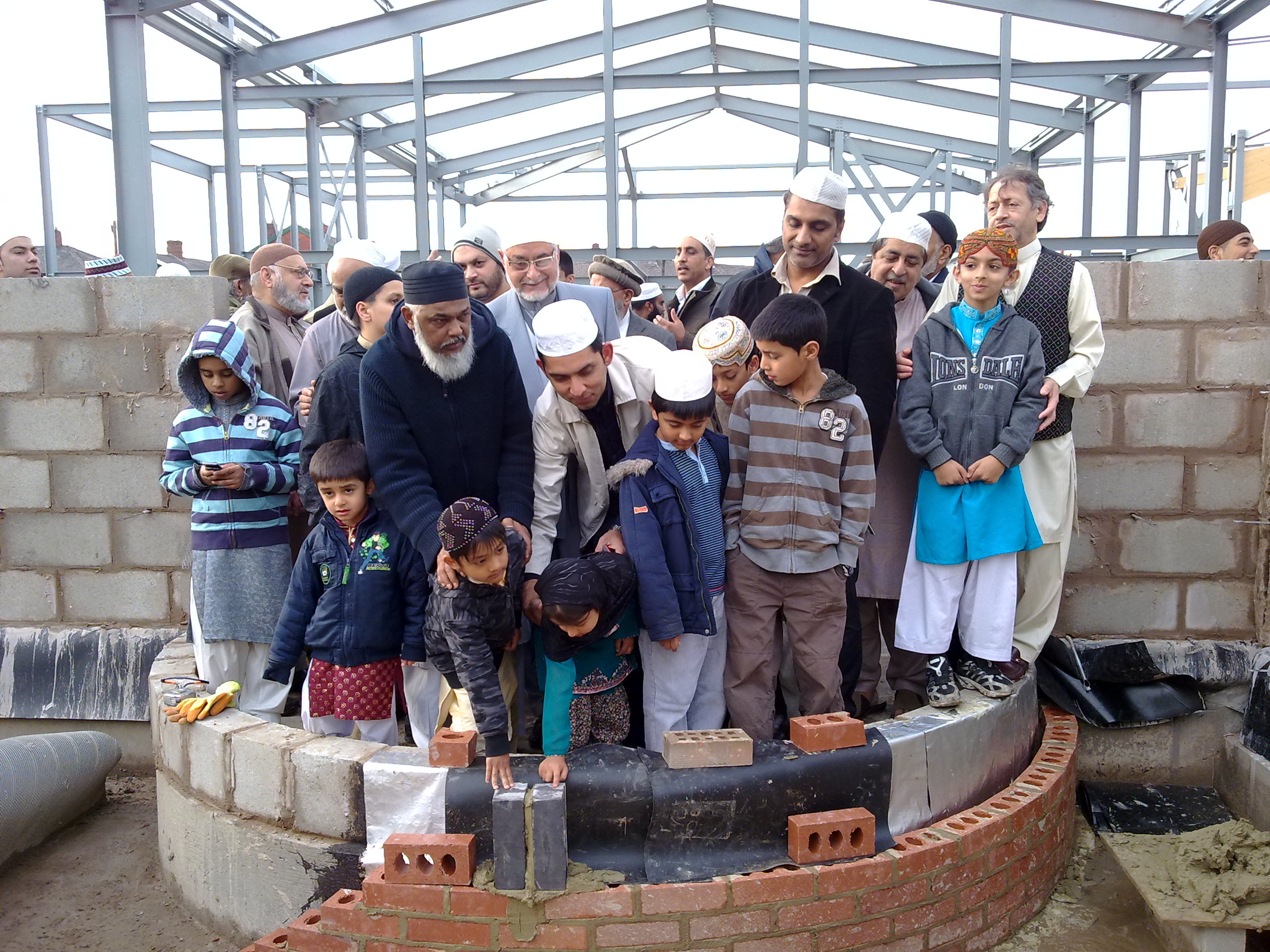 Community members and children at the brick-laying ceremony during mosque construction